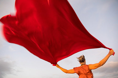 Woman holding up red cloth fluttering in wind Stock Photo - Premium Royalty-Free, Code: 649-09251401