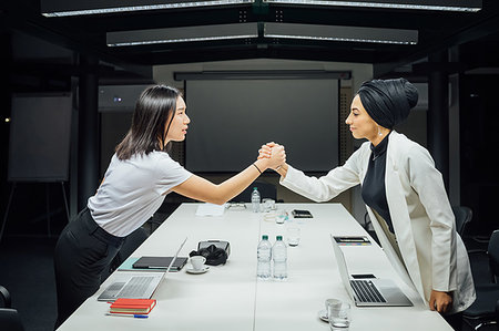 simsearch:649-09251667,k - Businesswomen shaking hands over conference table Photographie de stock - Premium Libres de Droits, Code: 649-09251678