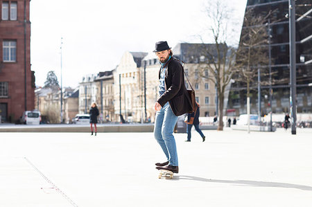 Man skateboarding in city square, Freiburg, Baden-Wurttemberg, Germany Stock Photo - Premium Royalty-Free, Code: 649-09251729