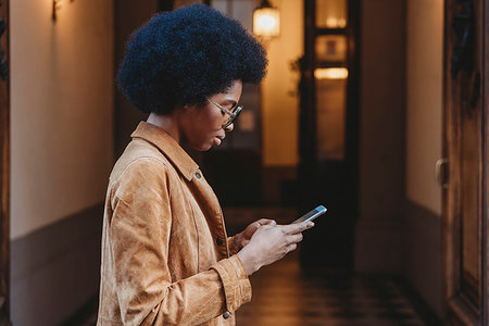 simsearch:649-09251527,k - Young woman with afro hair using smartphone in front of building Stock Photo - Premium Royalty-Free, Code: 649-09268444