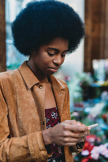 Young woman with afro hair using smartphone in city Stock Photo - Premium Royalty-Free, Image code: 649-09268459