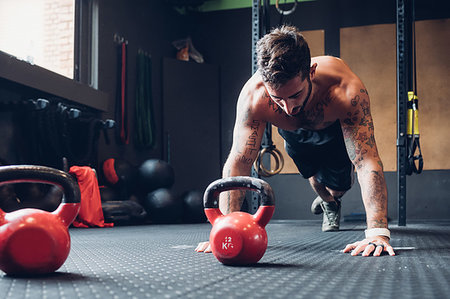 simsearch:649-08766513,k - Young man training in gym, doing push ups on floor Stock Photo - Premium Royalty-Free, Code: 649-09268826