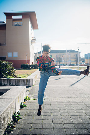 Young woman jumping and kicking leg on urban sidewalk, full length portrait Stock Photo - Premium Royalty-Free, Code: 649-09268919