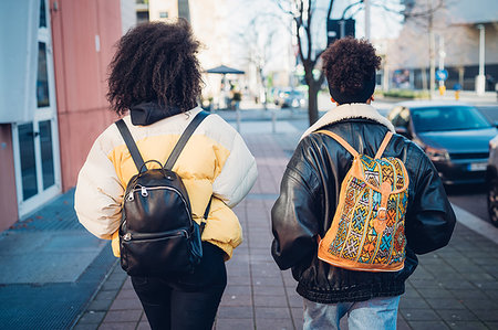 simsearch:649-09269203,k - Two young women carrying backpacks strolling on urban sidewalk, rear view Stock Photo - Premium Royalty-Free, Code: 649-09268942