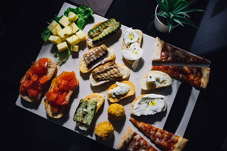 Shared platter with pizza, bruschetta and cheese on cafe table, overhead view Fotografie stock - Premium Royalty-Free, Codice: 649-09269045