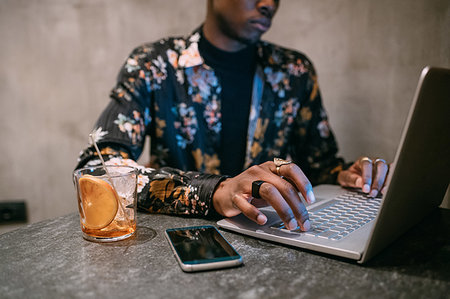 Stylish man enjoying drink while using laptop Foto de stock - Sin royalties Premium, Código: 649-09269199