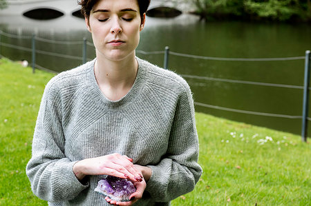 Woman practising Reiki on grass lawn by river, London, UK Stock Photo - Premium Royalty-Free, Code: 649-09269297