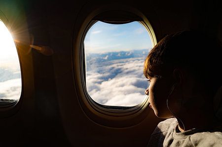 simsearch:649-08860216,k - Teenage boy looking out through airplane window at clouds on airplane journey Fotografie stock - Premium Royalty-Free, Codice: 649-09276162