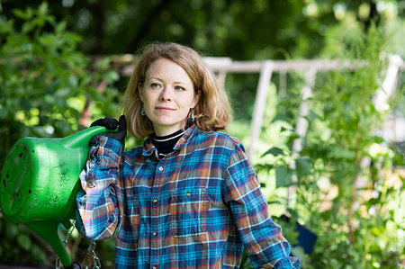 simsearch:649-09276174,k - Mid adult woman carrying watering can in her garden Photographie de stock - Premium Libres de Droits, Code: 649-09276186