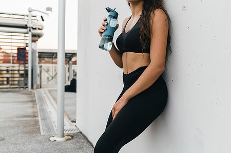 simsearch:6118-08129691,k - Young woman with water bottle leaning against wall on rooftop deck Foto de stock - Sin royalties Premium, Código: 649-09277716