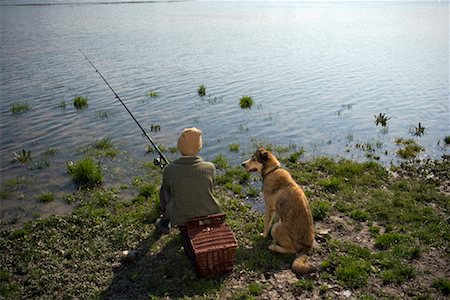 Boy (12-14) fishing by river with pet dog, rear view Stock Photo - Premium Royalty-Free, Code: 649-01556480