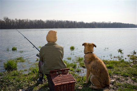 Boy (12-14) fishing by river with pet dog, rear view Stock Photo - Premium Royalty-Free, Code: 649-01556481