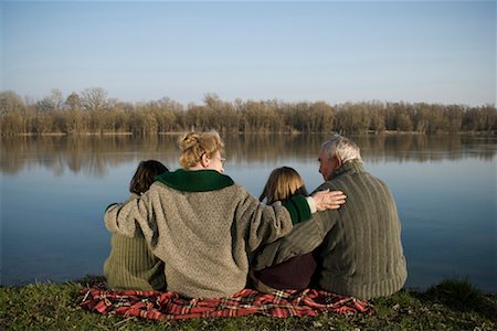 Grandparents, grandson (12-14) and granddaughter (10-12) sitting by river, rear view Stock Photo - Premium Royalty-Free, Code: 649-01556542