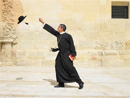 priest (christian) - Priest reaching for his hat blowing in the wind, Alicante, Spain, Stock Photo - Premium Royalty-Free, Code: 649-01557025