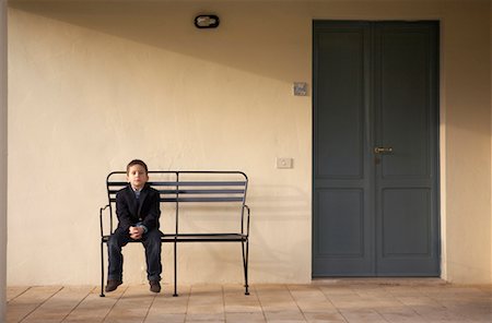 Boy (4-6) sitting on bench outdoors, portrait Stock Photo - Premium Royalty-Free, Code: 649-01557959