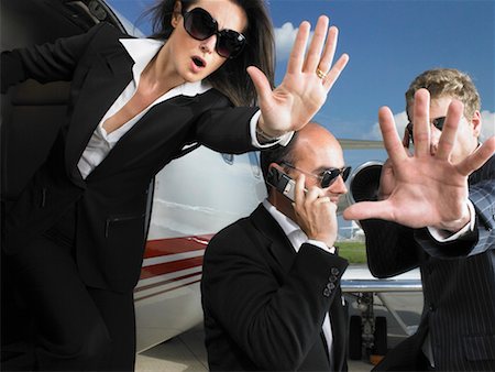 Two bodyguards defending businessman while exiting jet. Stock Photo - Premium Royalty-Free, Code: 649-01608658