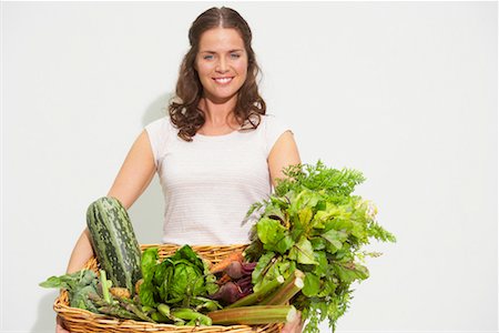 simsearch:649-08180659,k - Young woman with large basket of organic vegetables. Foto de stock - Royalty Free Premium, Número: 649-01609022