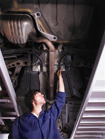 Mechanic standing under raised car Stock Photo - Premium Royalty-Free, Code: 649-01610378