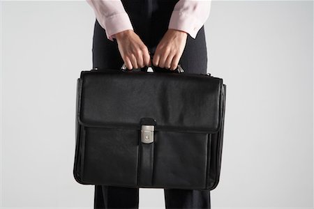 Woman holding a black brief case against her. Stock Photo - Premium Royalty-Free, Code: 649-01610632