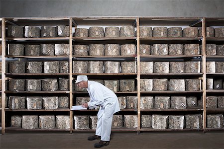 simsearch:649-07437202,k - Man with clipboard leaning down by rack of cheeses. Stock Photo - Premium Royalty-Free, Code: 649-01610651