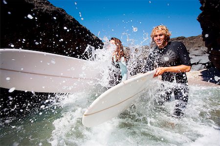 simsearch:649-01695983,k - Couple running in water with surfboards smiling. Fotografie stock - Premium Royalty-Free, Codice: 649-01695905