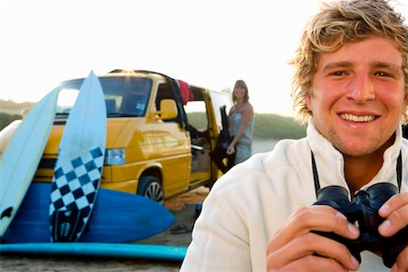 simsearch:649-01695983,k - Man on beach with binoculars smiling with woman unloading van at the beach . Fotografie stock - Premium Royalty-Free, Codice: 649-01695945