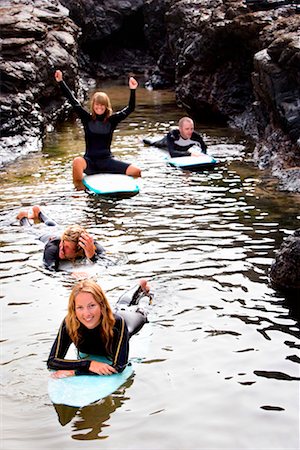 simsearch:649-01695983,k - Four people having fun on surfboards in the water smiling . Fotografie stock - Premium Royalty-Free, Codice: 649-01695984