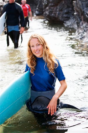 simsearch:649-01609553,k - Trois personnes portant des planches de surf à travers l'eau souriant. Photographie de stock - Premium Libres de Droits, Code: 649-01695980