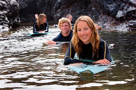 simsearch:649-01695983,k - Four people lying on surfboards in the water smiling . Fotografie stock - Premium Royalty-Free, Codice: 649-01695983