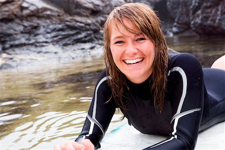 simsearch:649-01695983,k - Woman lying on surfboard in the water laughing. Fotografie stock - Premium Royalty-Free, Codice: 649-01695991