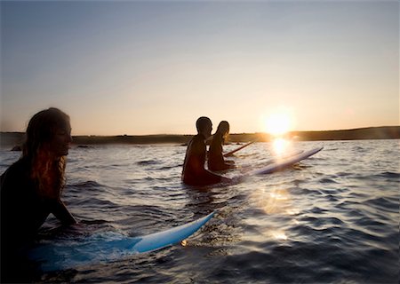 simsearch:649-01695983,k - Four people sitting on surfboards in the water smiling. Fotografie stock - Premium Royalty-Free, Codice: 649-01696034