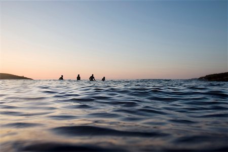 Four people sitting on surfboards in the water. Stock Photo - Premium Royalty-Free, Code: 649-01696035
