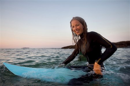 simsearch:649-01695983,k - Woman sitting on surfboard in the water smiling. Fotografie stock - Premium Royalty-Free, Codice: 649-01696039