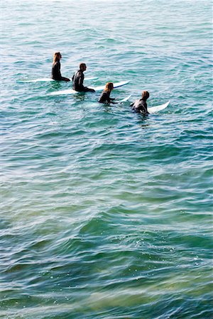 simsearch:649-01695983,k - Four people sitting on surfboards in the water. Fotografie stock - Premium Royalty-Free, Codice: 649-01696043