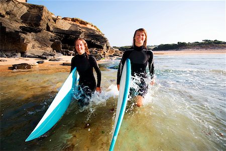 surfer running - Two women carrying surfboards in the water smiling. Stock Photo - Premium Royalty-Free, Code: 649-01696059