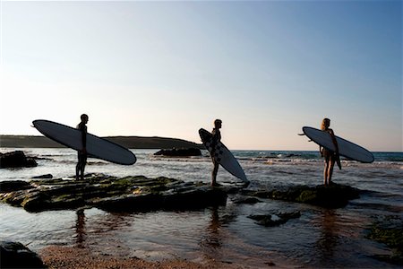 Three people holding surfboards standing on large rocks. Stock Photo - Premium Royalty-Free, Code: 649-01696094