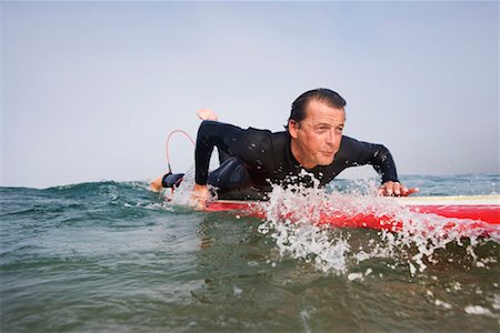 Man lying on surfboard in the water. Stock Photo - Premium Royalty-Free, Code: 649-01696148