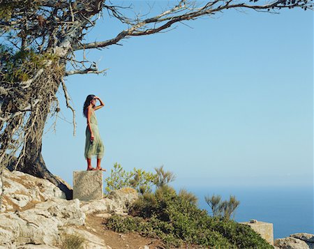 Woman standing on a large rock looking out over the sea. Stock Photo - Premium Royalty-Free, Code: 649-01696267