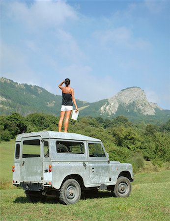 Woman standing on roof of SUV holding map. Stock Photo - Premium Royalty-Free, Code: 649-01696278