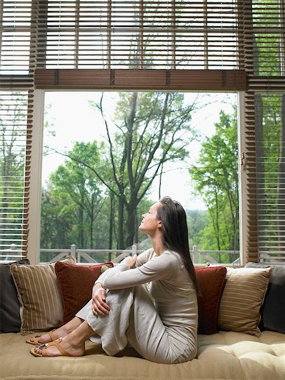 Woman with eyes closed sitting on sofa in living room. Photographie de stock - Premium Libres de Droits, Le code de l’image : 649-01696448