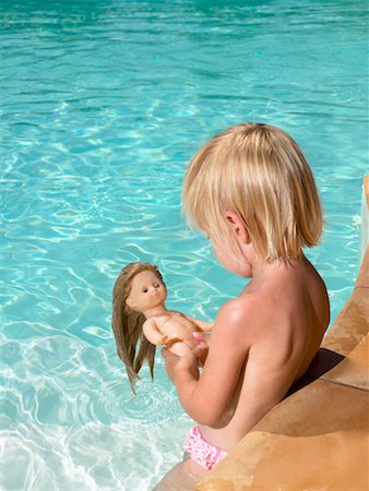 Young boy playing with a doll in a pool. Stock Photo - Premium Royalty-Free, Code: 649-01696507