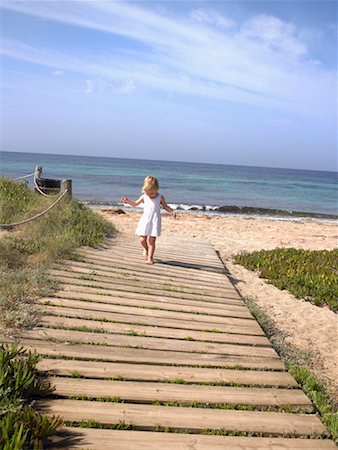 Jeune garçon marche sur un chemin en bois sur la plage. Photographie de stock - Premium Libres de Droits, Code: 649-01696519