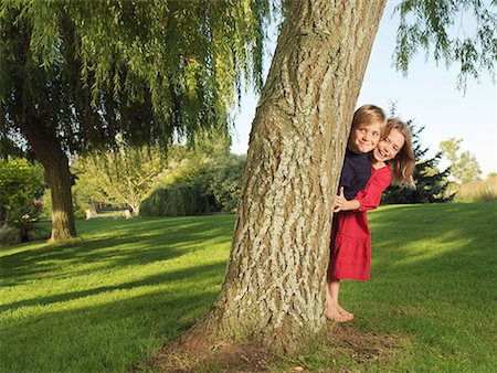 Jeune garçon et une fille se cachant derrière l'arbre Photographie de stock - Premium Libres de Droits, Code: 649-02053554