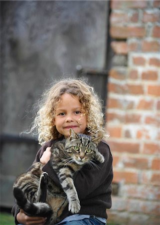 Young girl holding pet cat outside Fotografie stock - Premium Royalty-Free, Codice: 649-02423993