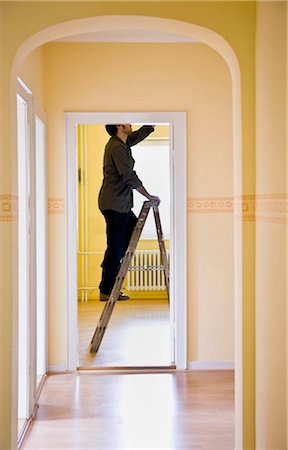 Man changing a light-bulb on a ladder Stock Photo - Premium Royalty-Free, Code: 649-02665380