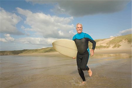 seniors surfing - Male running into sea with a surfboard Stock Photo - Premium Royalty-Free, Code: 649-02666199