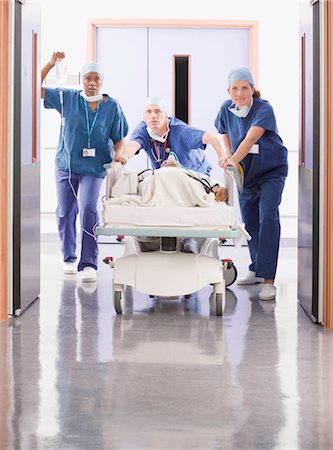 simsearch:614-02074408,k - Three doctors pushing a patient in bed Fotografie stock - Premium Royalty-Free, Codice: 649-02666333