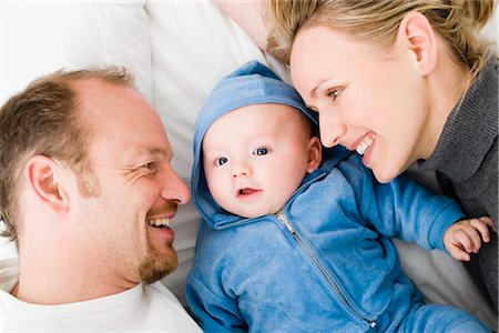 side profile of woman in hoodie - Baby laying between dad and mom Stock Photo - Premium Royalty-Free, Code: 649-02731350