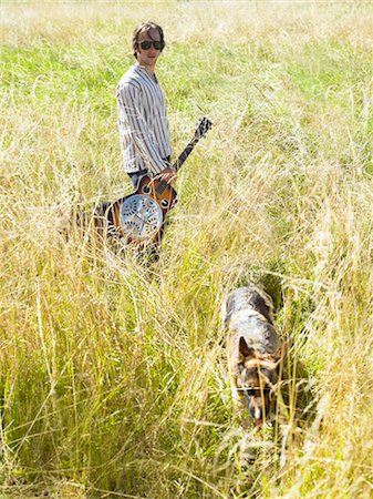 Man with his guitar and dog in a field Foto de stock - Sin royalties Premium, Código: 649-02731846