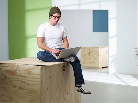 recycling computers - Young man sitting on box with laptop Stock Photo - Premium Royalty-Free, Code: 649-02733113